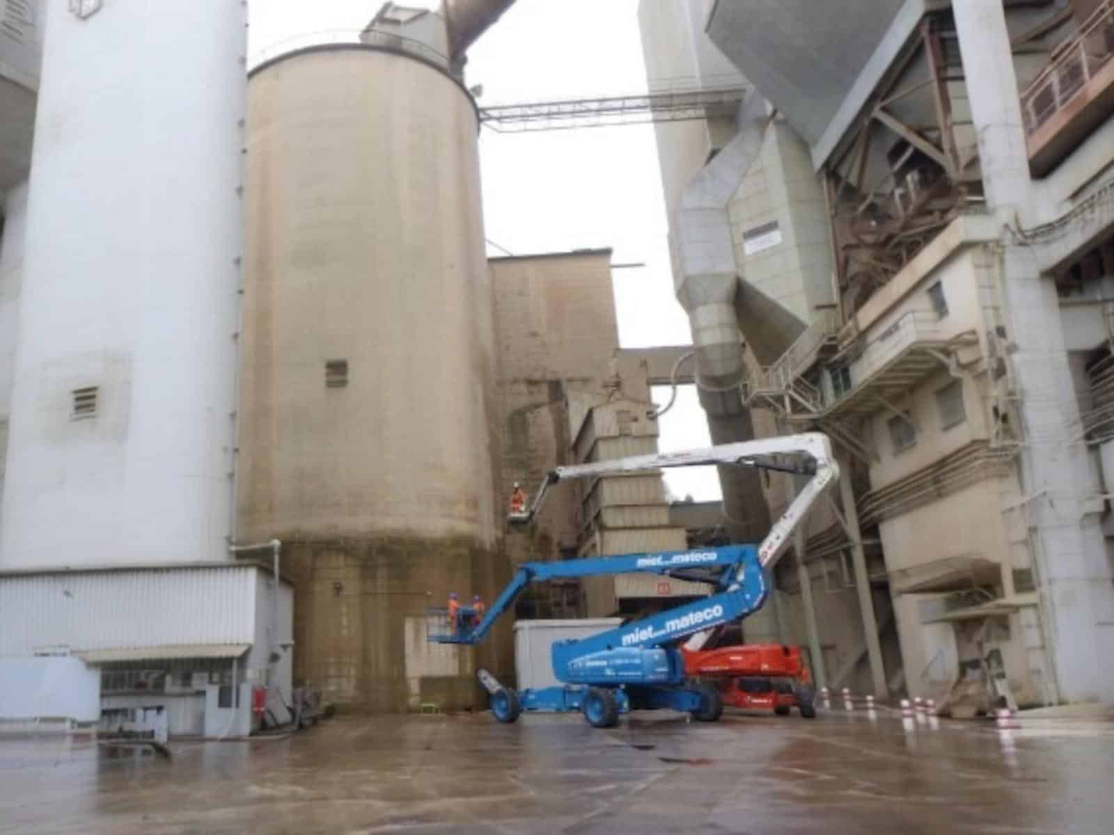 Panoramic view of cement plant with four silos undergoing robotic inspection